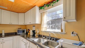 A kitchen with white cabinets, granite countertops, a double sink, a microwave, and a window with a view of trees. - 8 Mi to Appalachian Trail! Home w/ Fire Pit (Ceres)