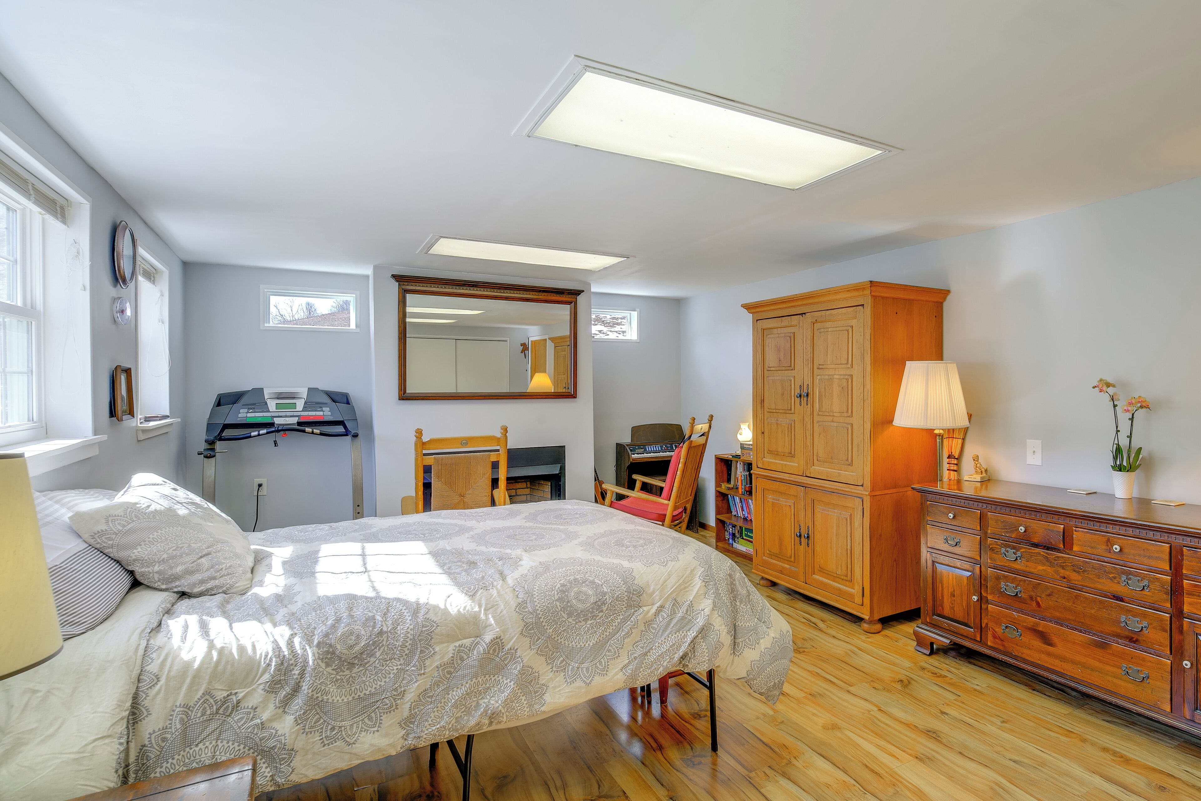 A bedroom with a bed, a dresser, a desk, a chair, a mirror, and a window.