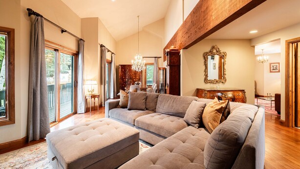 Ein geräumiges Wohnzimmer mit Ecksofa, Hocker und einer Chandelier.