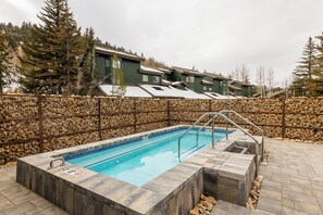 A rectangular outdoor swimming pool with a stone border, surrounded by a stone wall and a metal fence. - Short walk to Deer Valley ,Shuttle, Garage, Hot Tub (Park City)