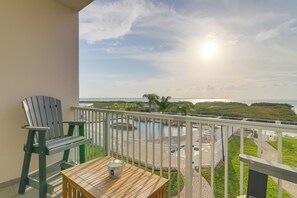 A balcony with a view of a swimming pool and a distant bridge. - Bay Front Luxury: Sunset Balcony Over Pool, Boats (South Padre Island)