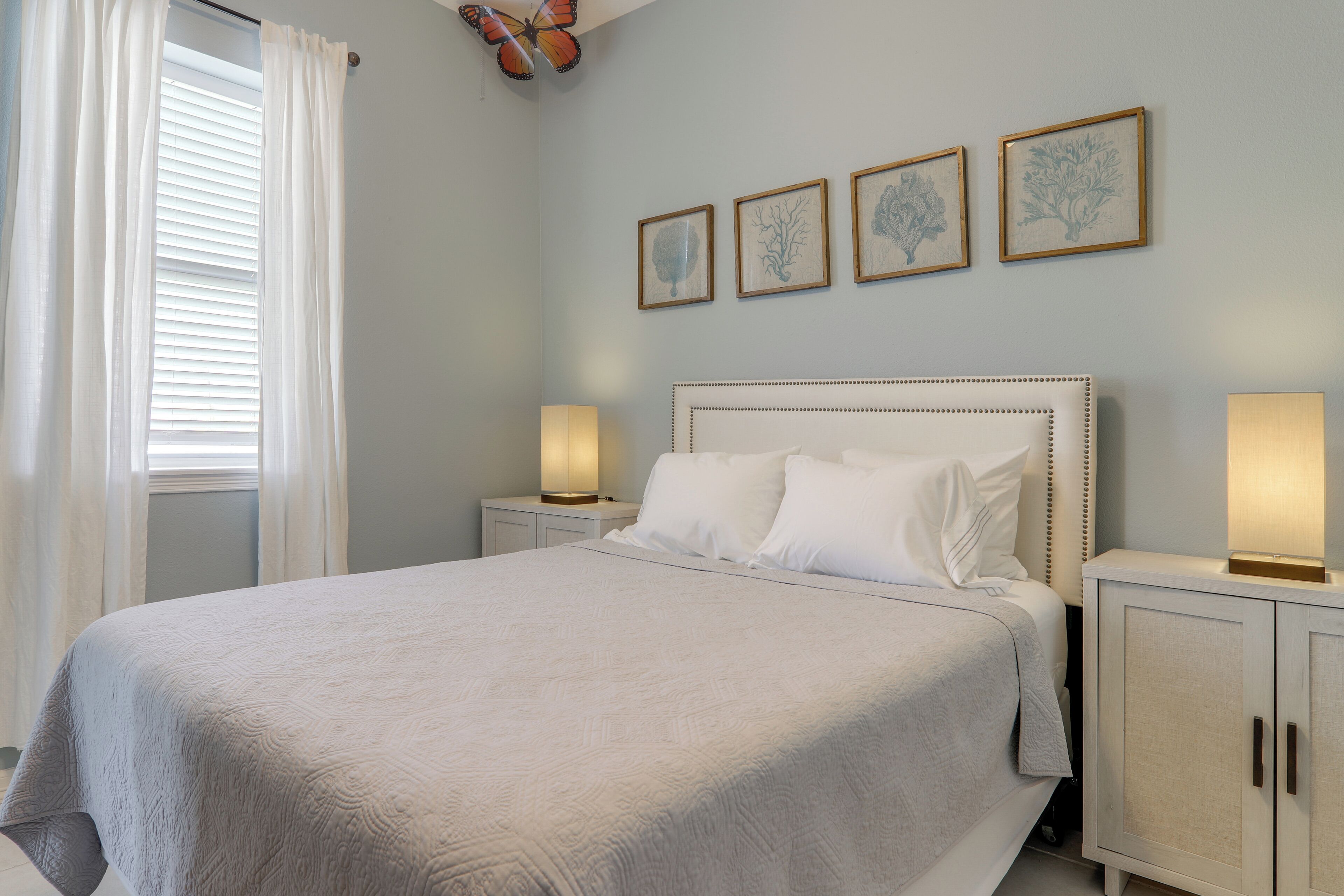 A bedroom with a large bed, two bedside tables, and wall-mounted artwork.