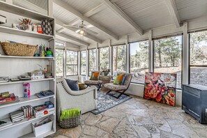 A sunlit reading room with bookshelves, comfortable seating, and a large window offering a view of trees. - 'the Restful Retreat' Mtn-view Alto Group Getaway (Alto)