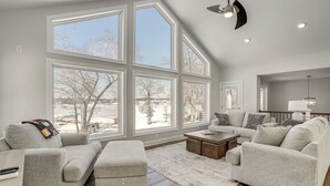 Un salon spacieux doté de grandes fenêtres, d’un plancher en bois et d’un ventilateur de plafond moderne.