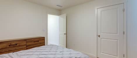 A bedroom with a bed, a wooden dresser, and a white door.