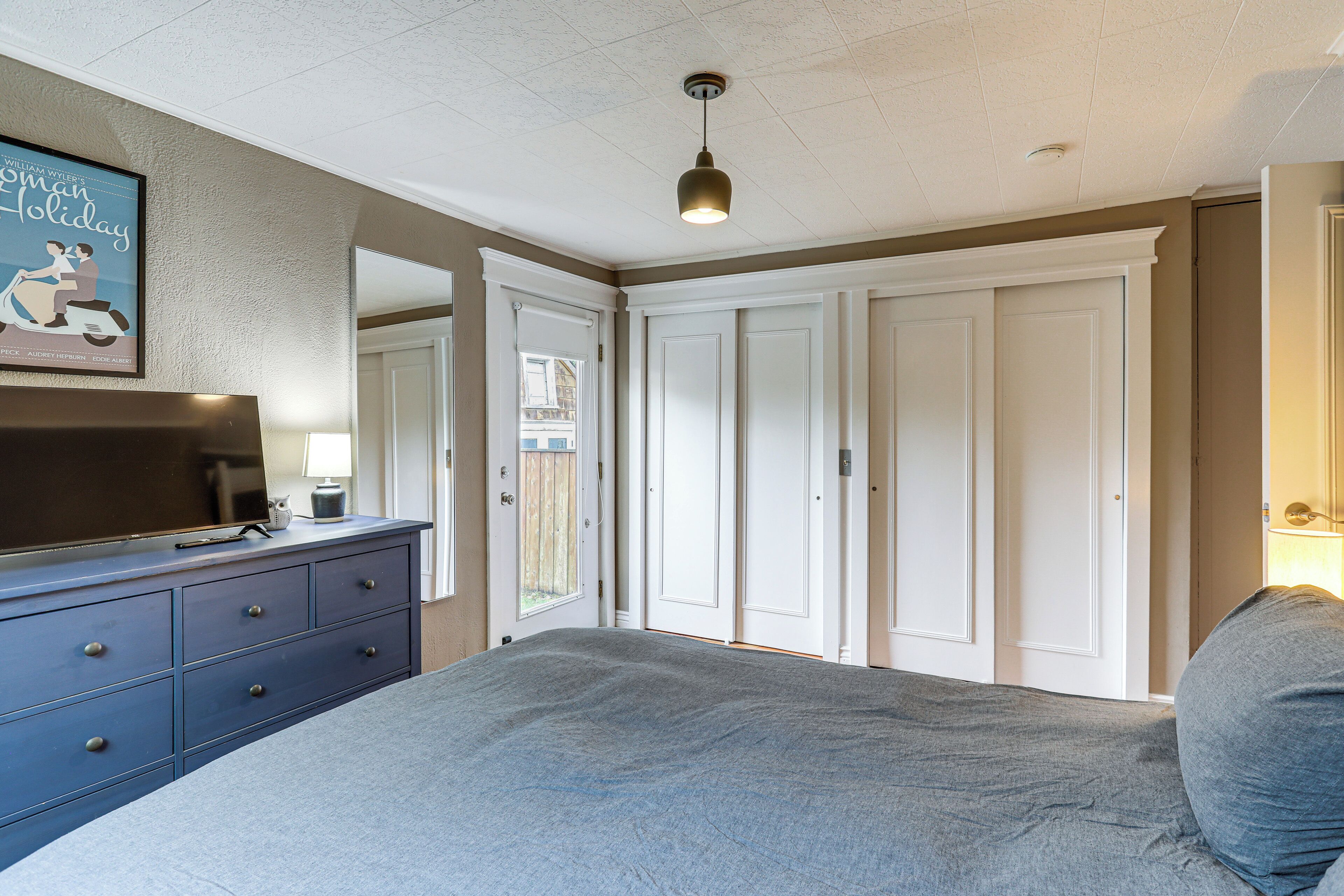 A bedroom with a bed, a dresser, a television, and a closet.