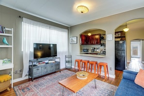 A living room with a TV, sofa, coffee table, and bar stools. - 8 Mi to Lumen Field! Walkable Home w/ Fenced Yard (Seattle)