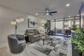 A modern living room with a leather sofa, a round coffee table, and a ceiling fan. - Renovated, Walkable! Old Town Condo w/ Pool Access (Scottsdale)