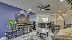 Ein modernes Wohnzimmer mit Flachbildfernseher, Deckenventilator und Essbereich mit Stühlen und Tisch.