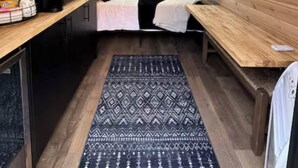 A cozy attic bedroom with a sloped ceiling, a bed with pillows, a small table with a kettle, and a window. - NEW! Unique Modern Glamping Chalet #3 (Orderville)