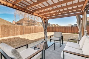 Ein überdachter Außenbereich mit Holz-Pergola, einem Glastisch und zwei Sofas.