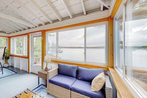 A cozy room with a blue cushioned bench, large windows, and a view of a lake. - 3BR Lakefront Dog-friendly w/ Dock (Dexter)