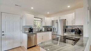 Una cocina moderna con armarios blancos, electrodomésticos de acero inoxidable y encimera de mármol.