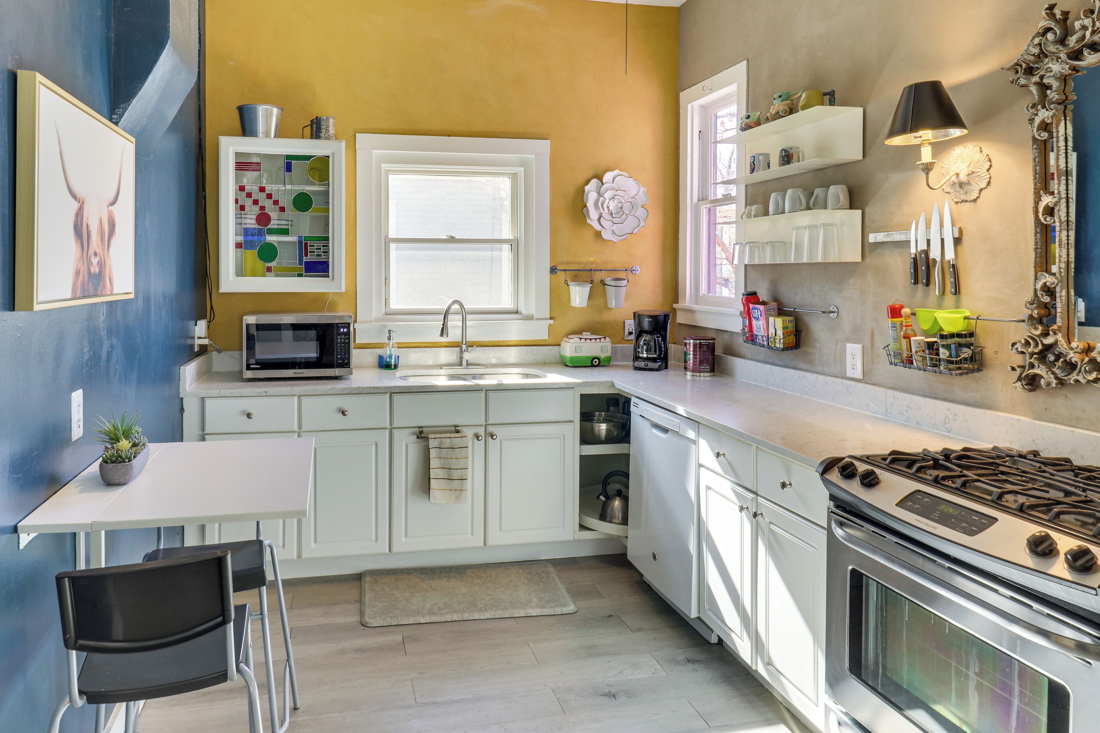 Une cuisine moderne avec des meubles blancs, une cuisinière en acier inoxydable, un four à micro-ondes et un évier.
