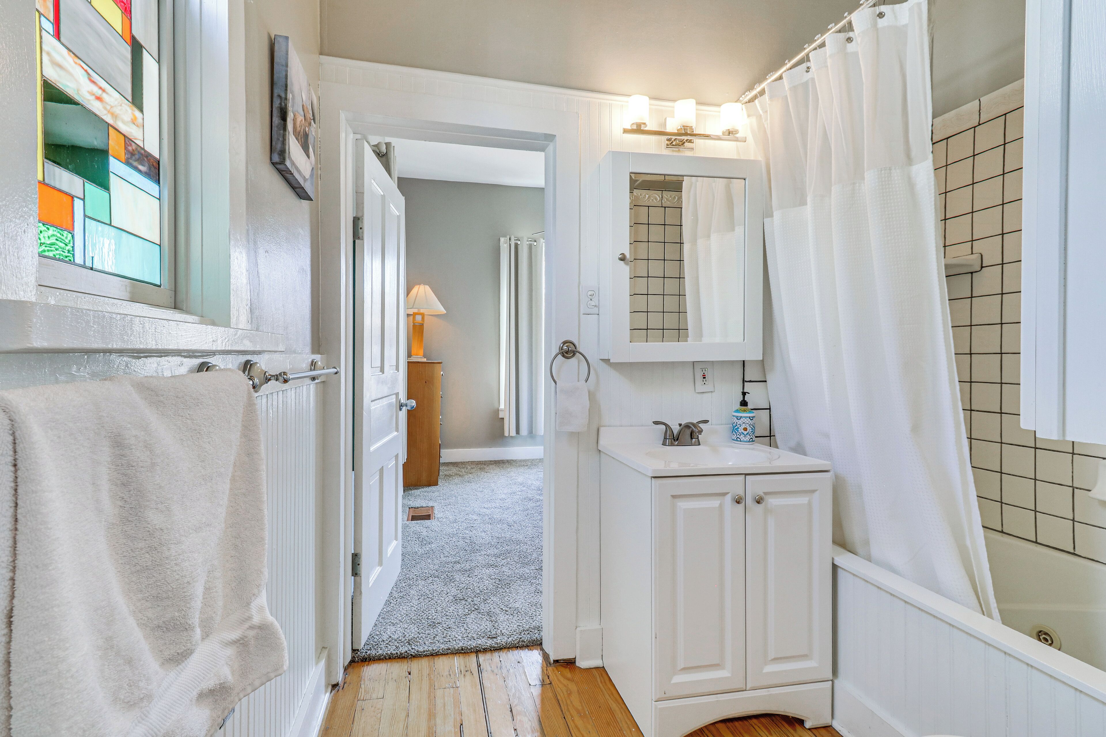 A bathroom with a white vanity, a shower curtain, and a tiled wall.