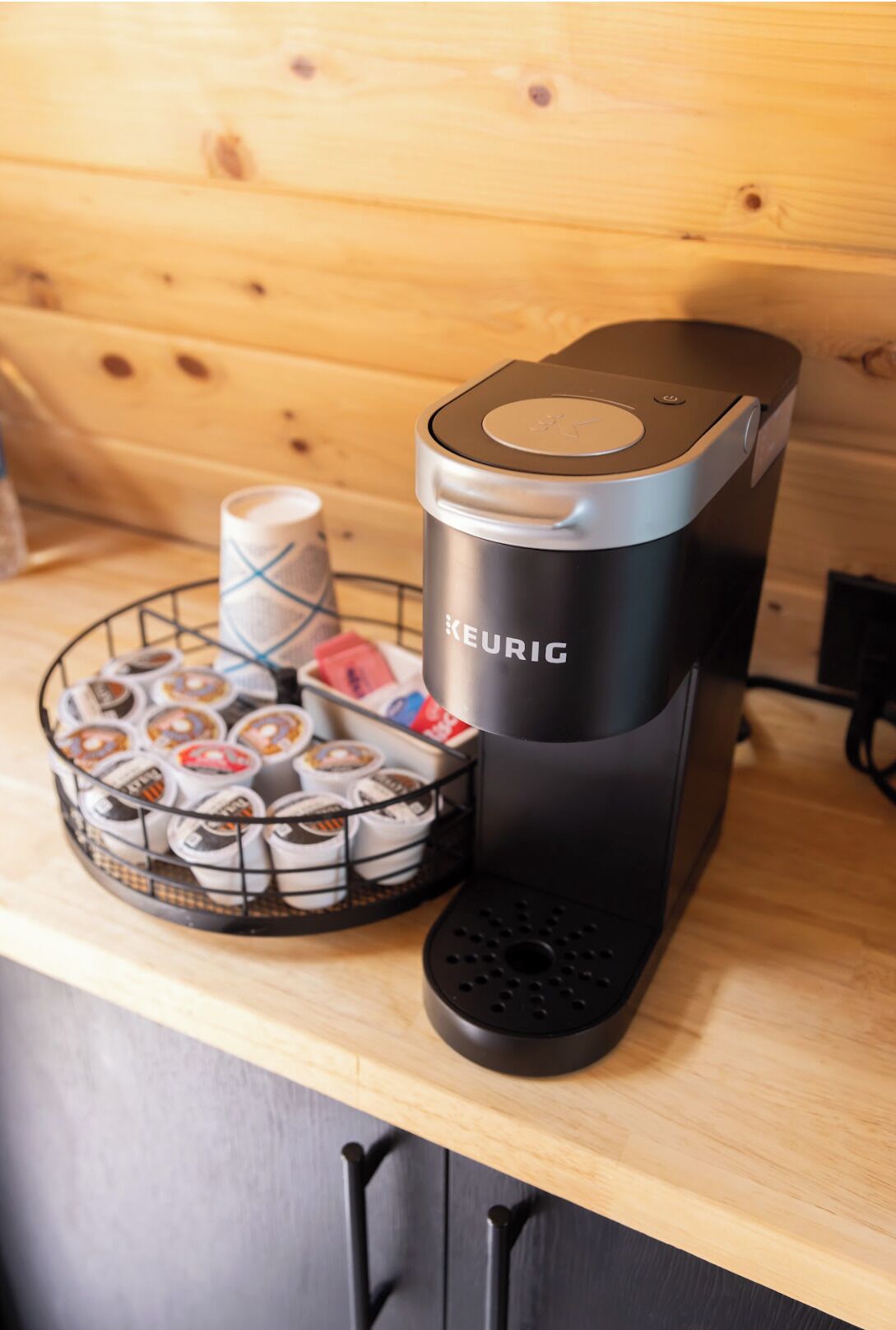 A Keurig coffee maker on a wooden countertop with a basket of coffee pods.
