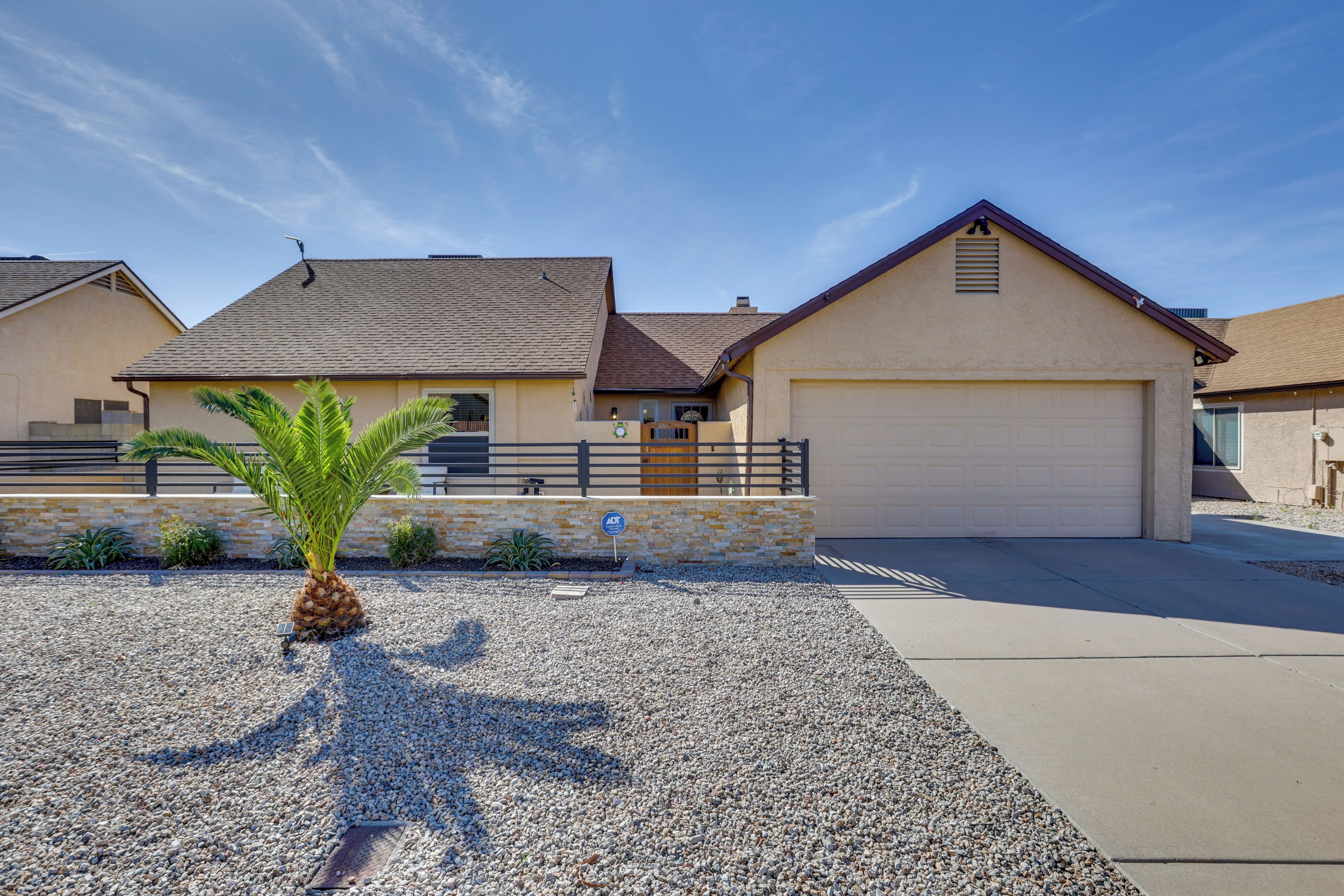 A residential house with a garage, a driveway, and a palm tree.