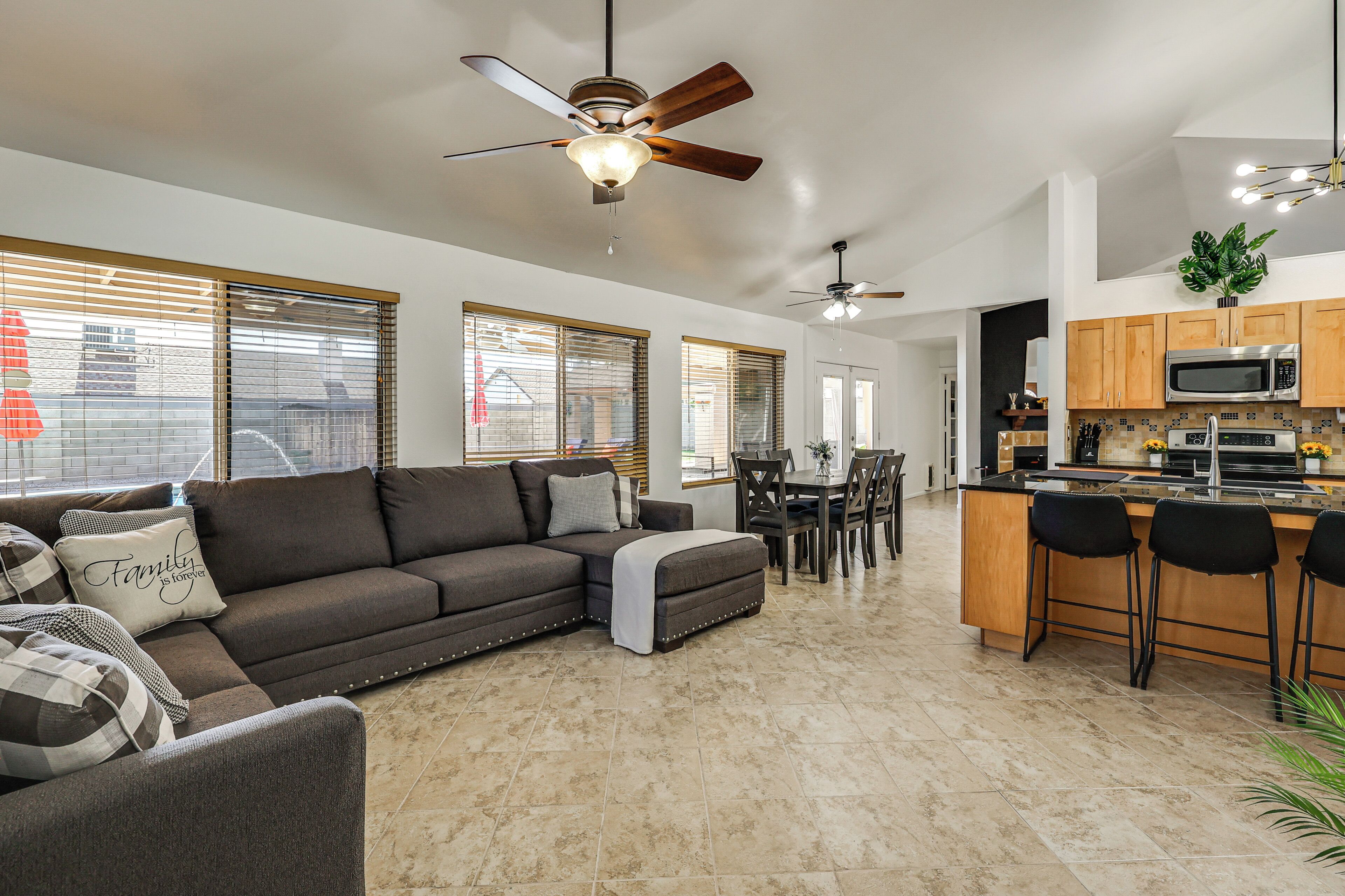 A modern living room with a sofa, ottoman, and dining area with chairs and a table.