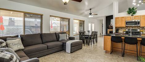 A modern living room with a sofa, ottoman, and dining area with chairs and a table.
