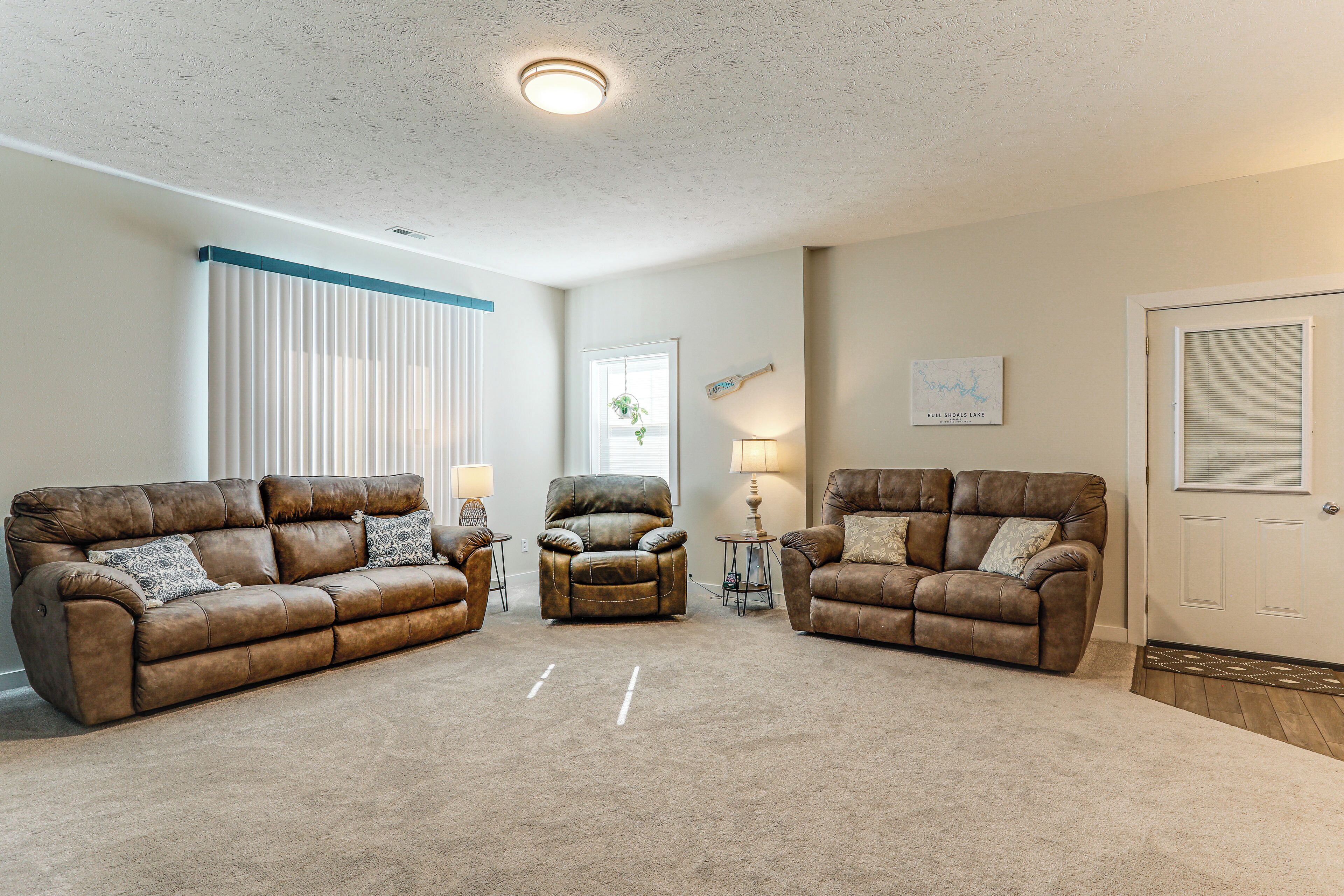 A living room with two brown leather sofas, a brown leather chair, and a white ceiling with a light fixture.