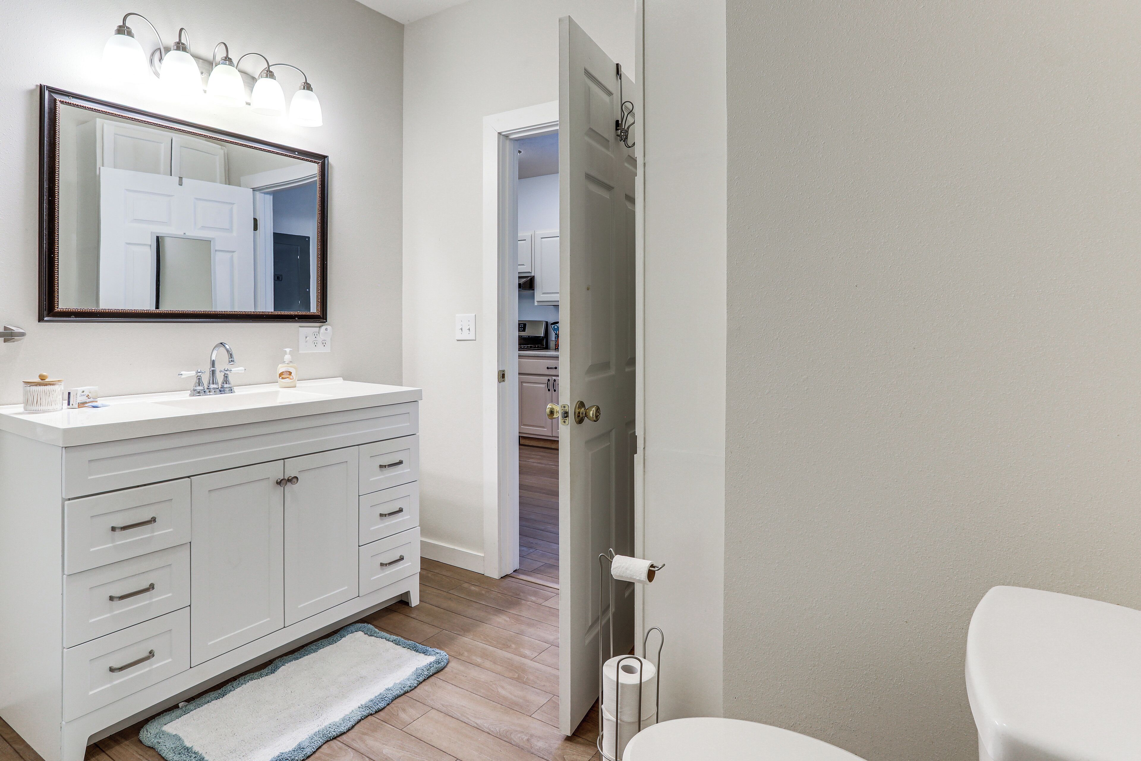 A bathroom with a white vanity, a large mirror, and a toilet.