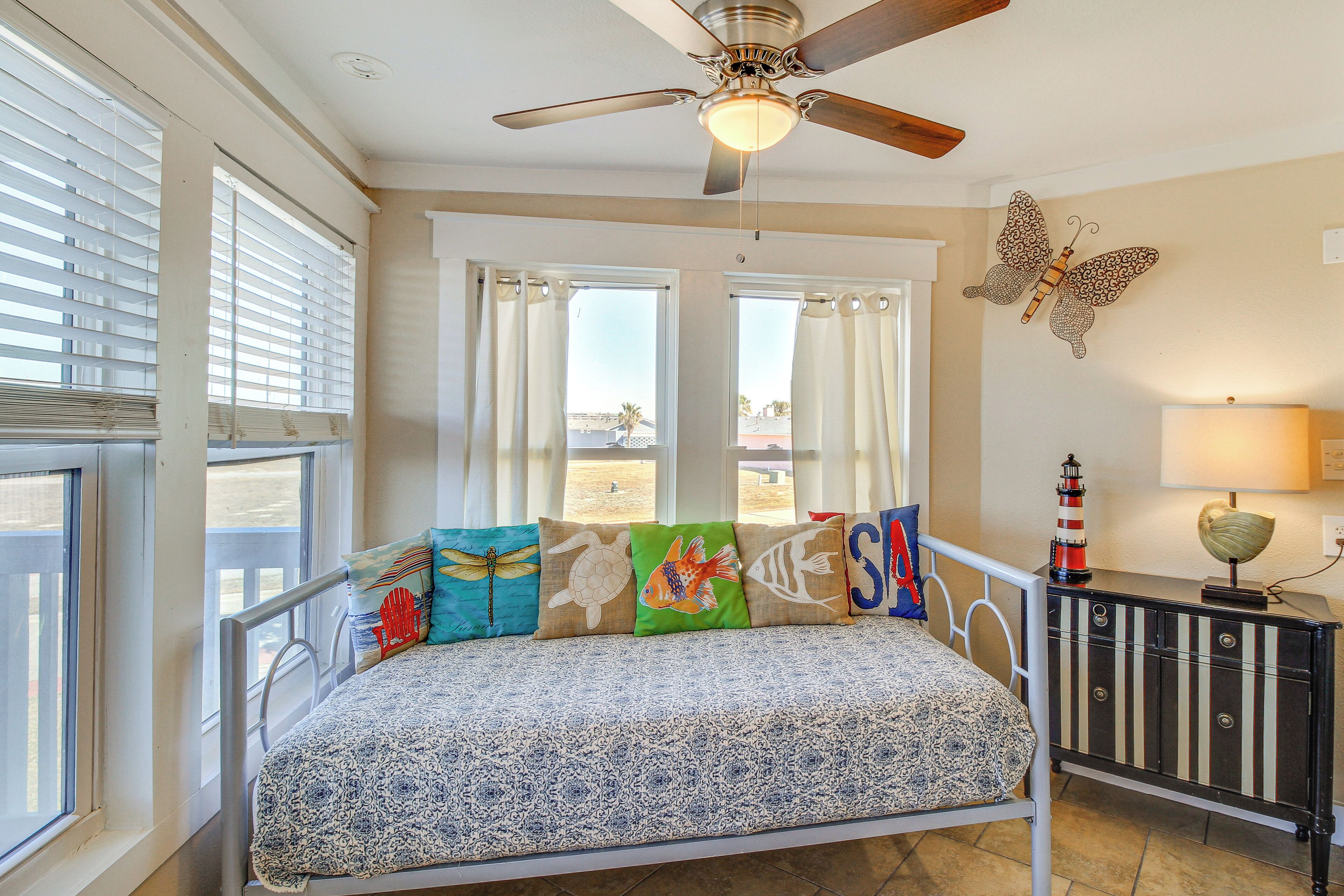 A bedroom with a bed, a ceiling fan, a window with blinds, and a decorative butterfly on the wall.