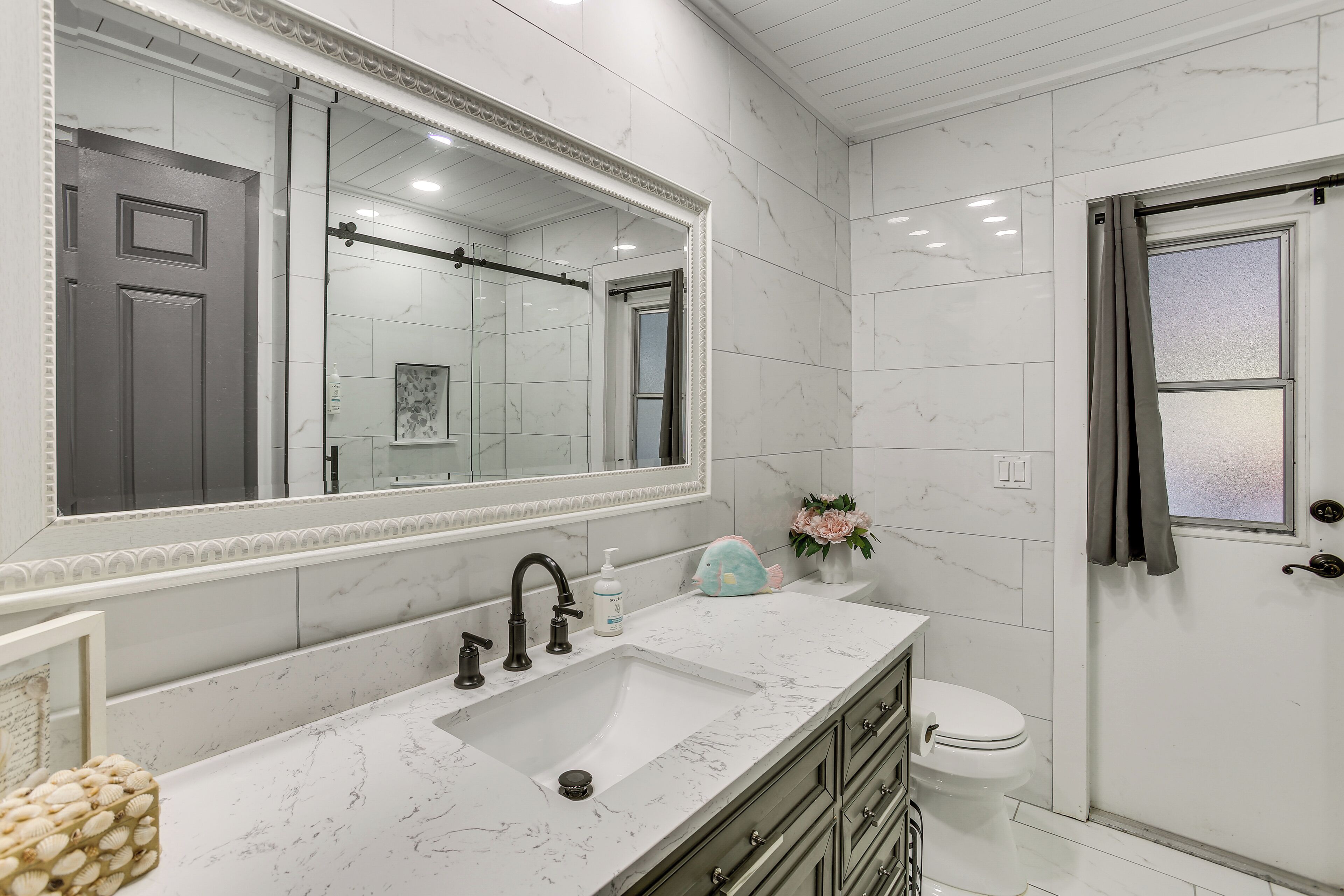A bathroom with a marble sink, a large mirror, a toilet, and a shower area.