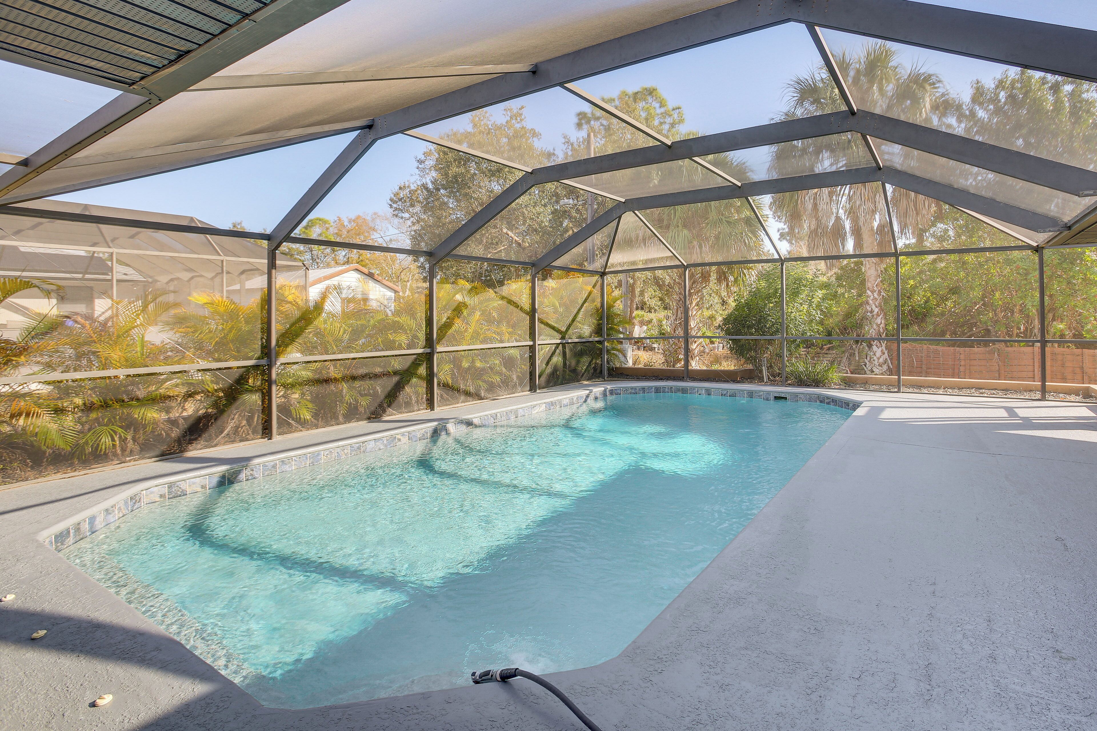 An indoor swimming pool with a glass ceiling, surrounded by palm trees and a brick wall.