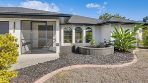 A modern house with a patio, a covered entryway, and a landscaped garden.