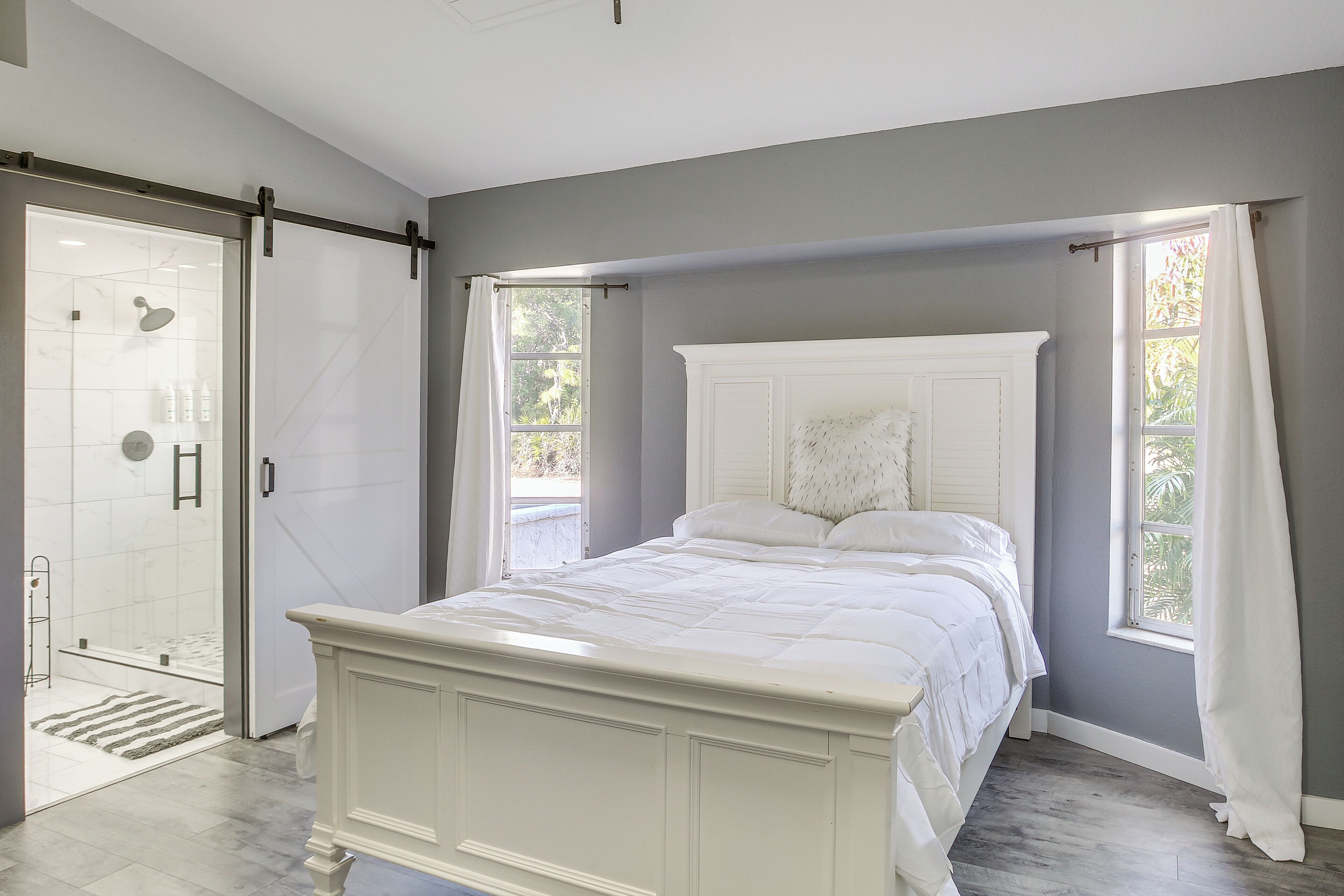 A bedroom with a large bed, a walk-in closet, and a sliding glass door leading to a shower area.