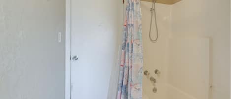 Un bagno con doccia, una porta e una vasca da bagno.