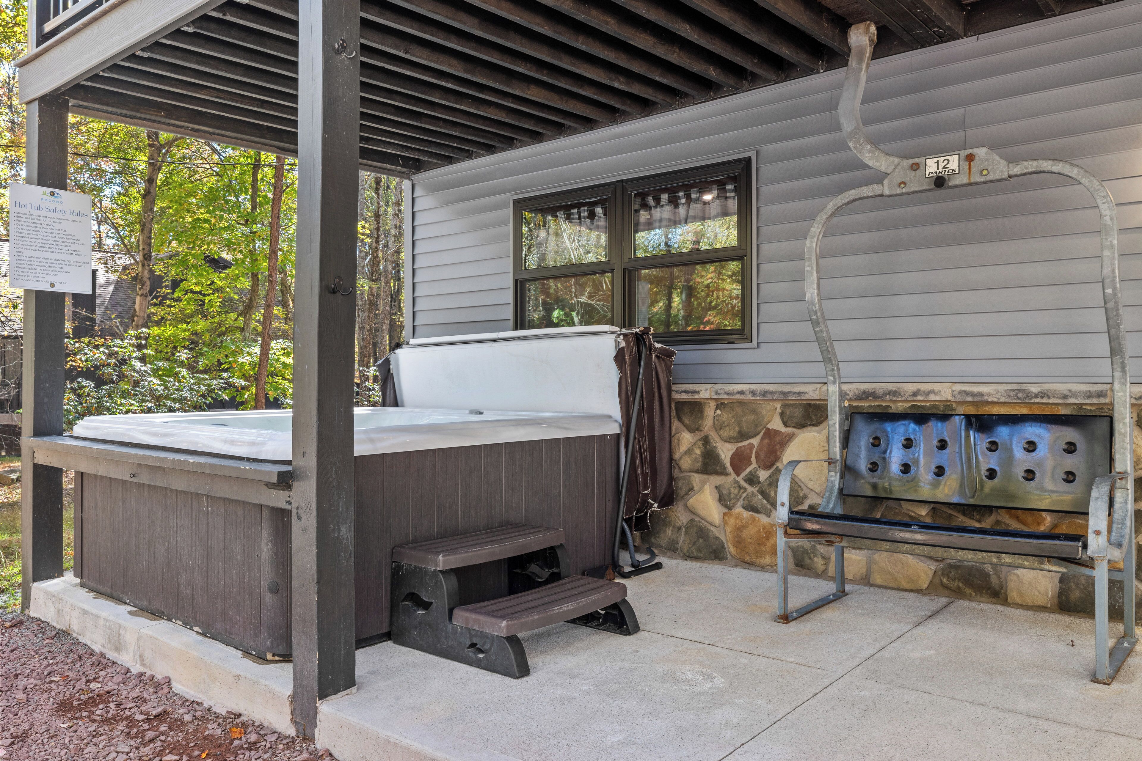 A hot tub with a stone wall and a metal grill attached to the wall.