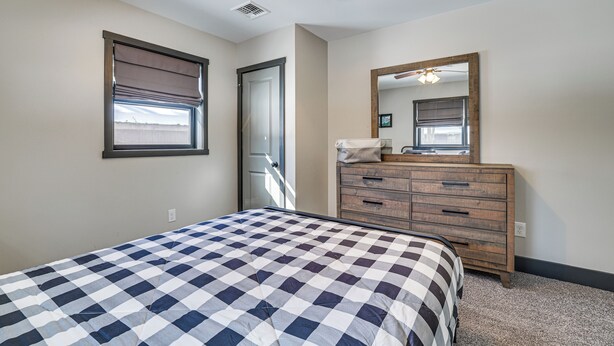 Ein Schlafzimmer mit Bett, Kommode, Spiegel und Deckenventilator.