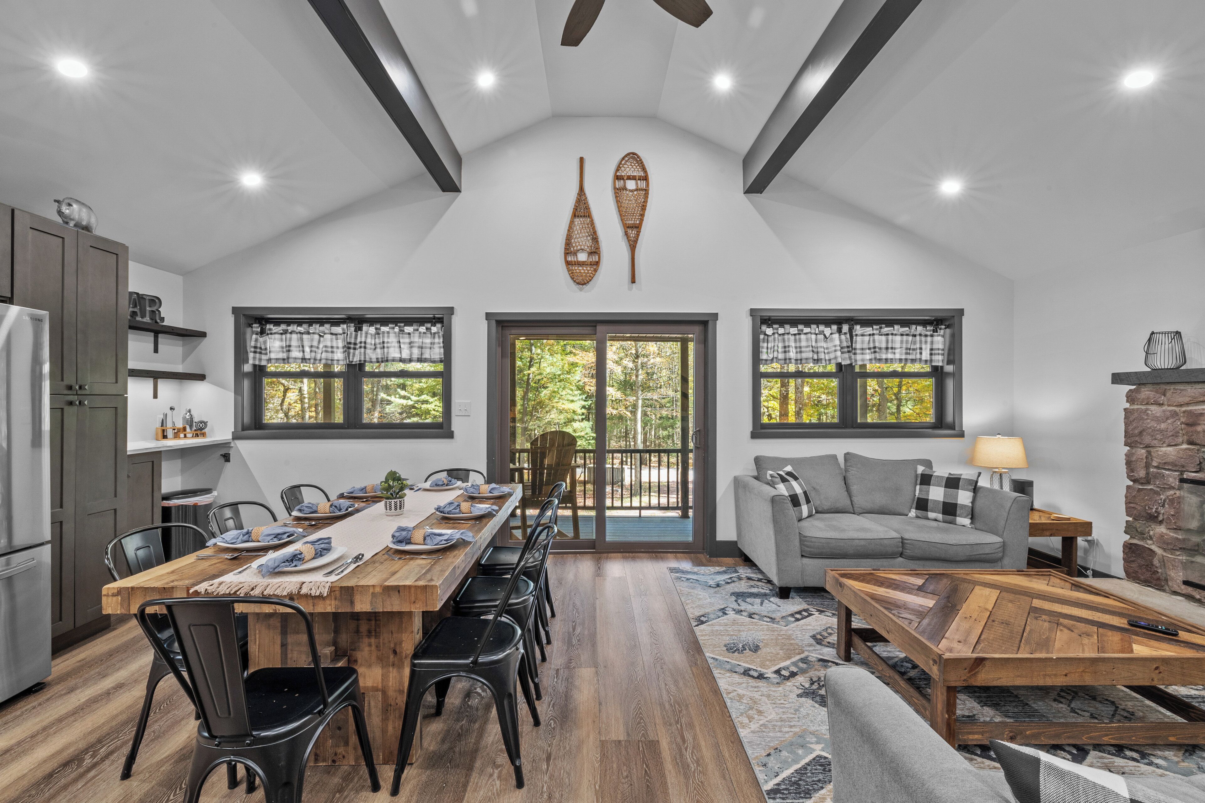 A spacious kitchen with a dining area, large windows, and a stone fireplace.