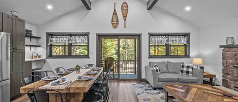 A spacious kitchen with a dining area, large windows, and a stone fireplace.