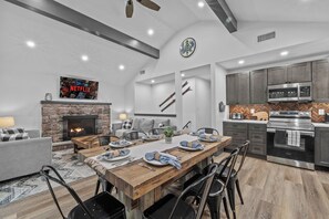 A modern kitchen with built-in appliances, a dining area with a wooden table, and a fireplace. - Poconos Ski Base w/ Hot Tub & Game Room! (Lake Harmony)