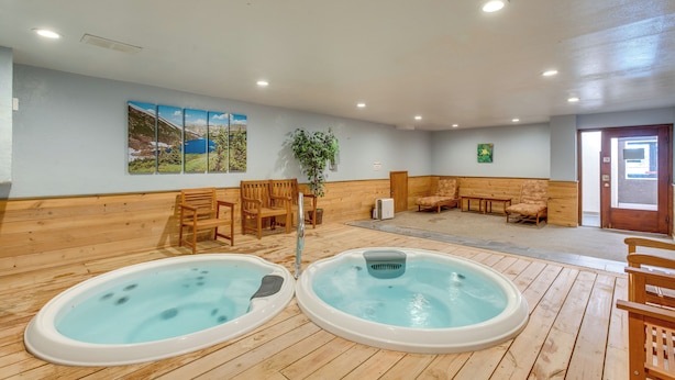 A spa area with two hot tubs, wooden flooring, seating, and a painting on the wall. - Walk to Main St! Ultimate Winter Park Getaway (Winter Park)