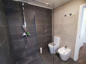 Ein modernes Badezimmer mit Dusche, Toilette, Bidet und Handtuchhalter.