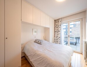 A bedroom with a bed, a window with curtains, and a view of the outside. - Spacious Modern Apartment in Knokke-heist (Knokke-Heist)