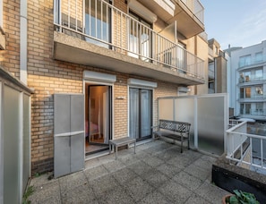 A two-story apartment building with a balcony, a sliding door entrance, and a small outdoor seating area. - Spacious Modern Apartment in Knokke-heist (Knokke-Heist)