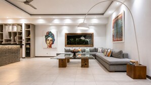 A modern living room with a sofa, coffee table, and artwork on the walls. - Elegant 3BR Oasis in the Heart of Seminyak (Kuta Utara)