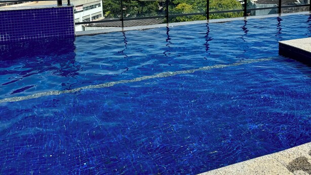 A rooftop infinity pool with a city view, surrounded by buildings and a clear sky. - Cozy NEW apartment in Ondina (Salvador)