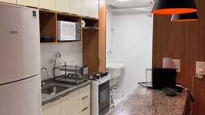 A modern kitchen with white cabinets, a built-in microwave, a gas stove, and a sink. - Cozy NEW apartment in Ondina (Salvador)