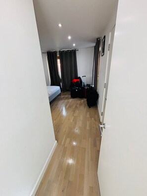 A hotel room with a wooden floor, a bed, a suitcase, and a radiator. - Amazing 2 Bed Bath Flat with London Eye View LM7 (London)