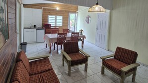 A spacious living area with a sofa, armchairs, and a dining table. - Chalet les planifolias, landscaped garden, access to numerous paths, sea and mountains. (Saint-Philippe)