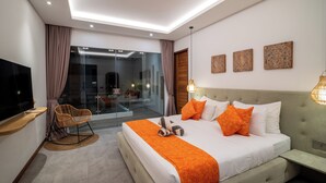 Una habitación de hotel moderna con una cama grande, televisor, zona de estar y puerta de cristal que da a un balcón.