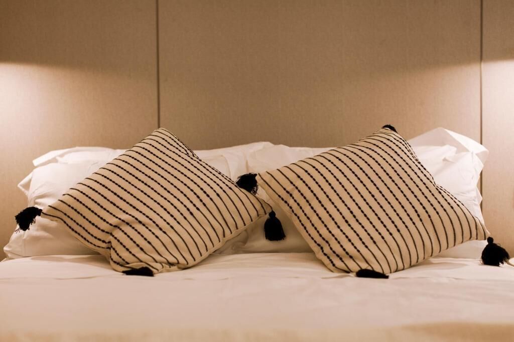 A bed with two striped pillows and a white blanket.