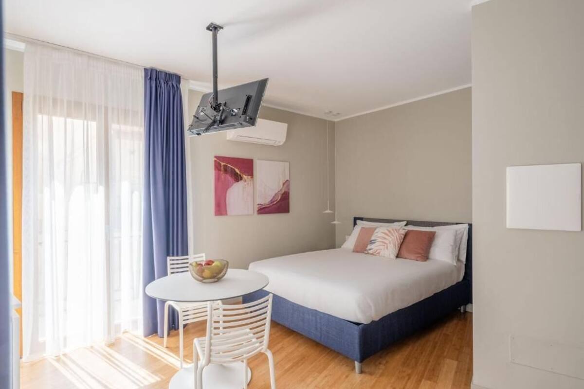 Un dormitorio moderno con una cama, una mesa redonda con sillas y un ventilador de techo.