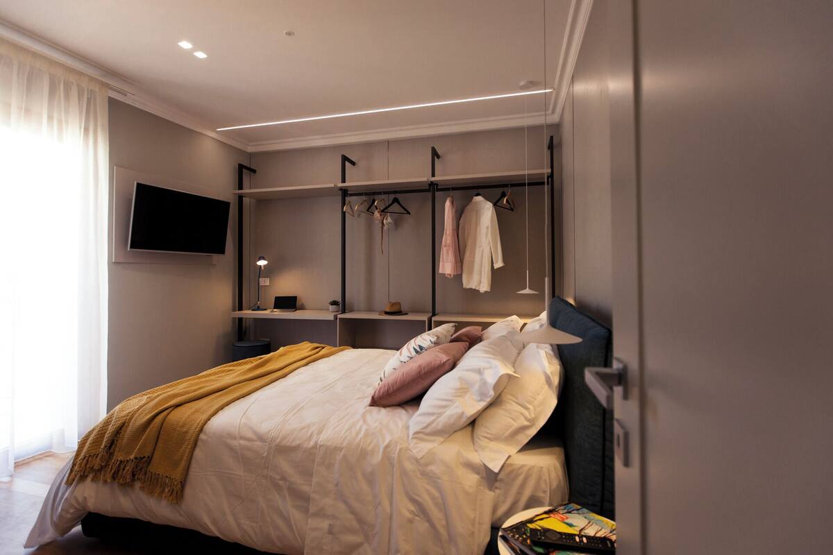 Un dormitorio moderno con cama, mesitas de noche, televisor y armario.