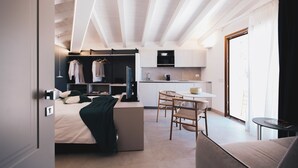 Ein modernes Hotelzimmer mit Bett, Sitzecke, Küchenzeile und Kleiderschrank.